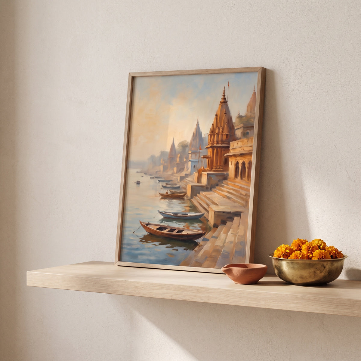 Framed Varanasi ghats painting on a wooden shelf with a terracotta diya and marigolds